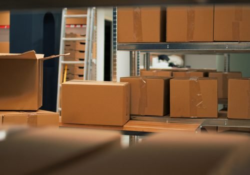 Empty storage space filled with stacks of merchandise and goods, shelves and racks of products in storehouse room. Warehouse used to deliver goods to customers working on logistics.